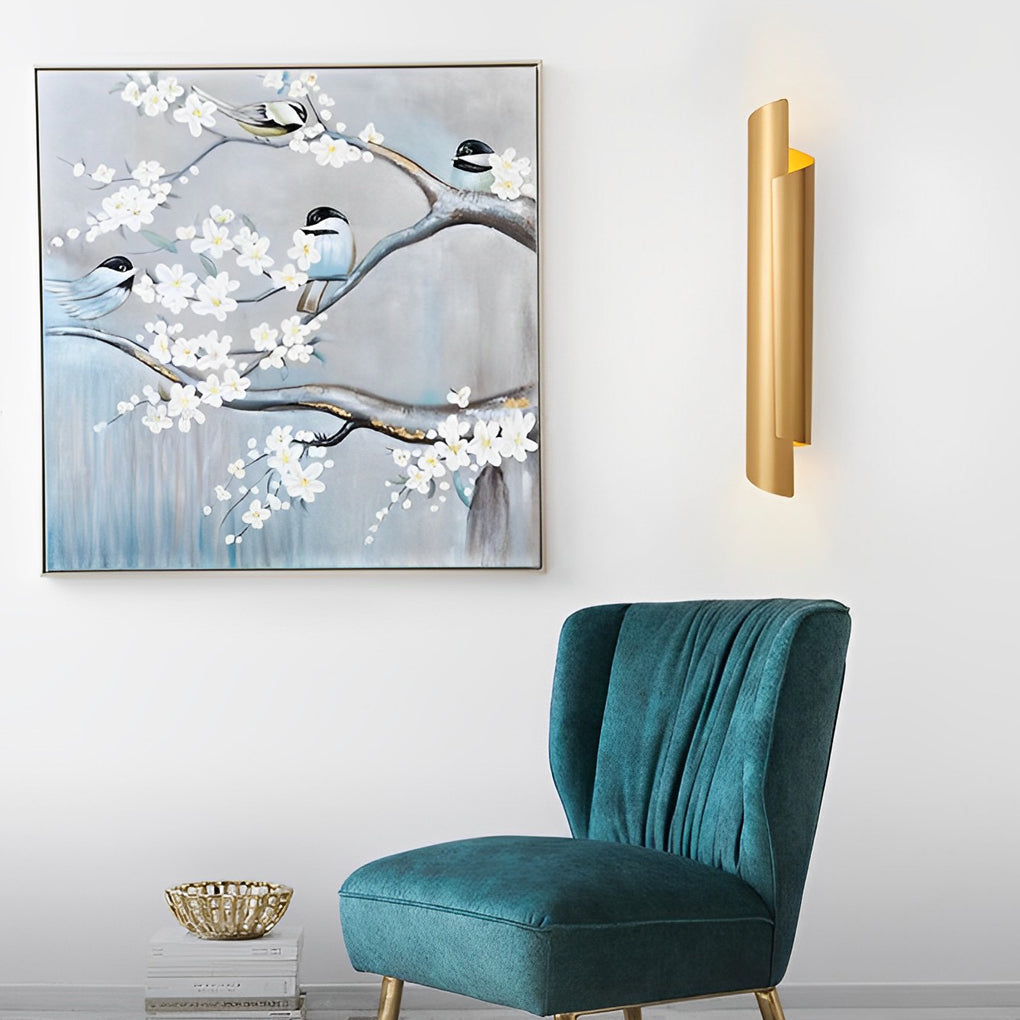 Scroll wall sconce in black and gold, mounted above a sofa, adding warmth to a contemporary living space.