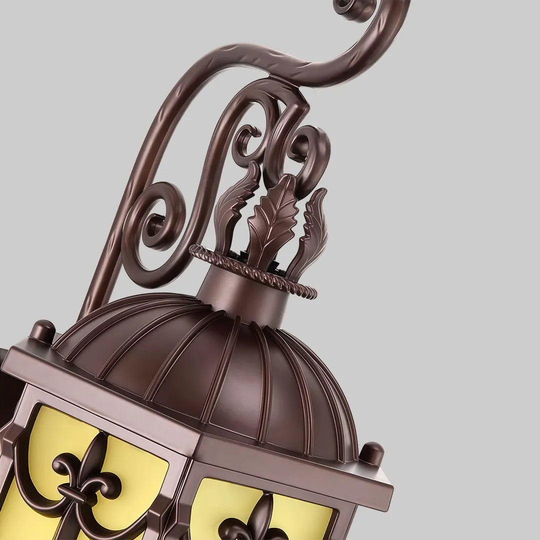 Close-up of vintage wall sconce lighting showing the ornate scroll arm and decorative bronze top.