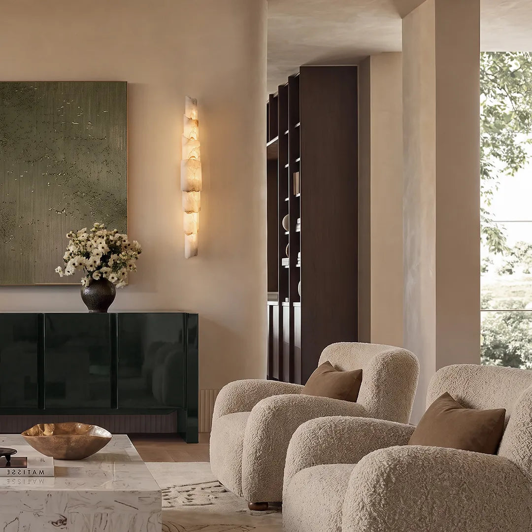 Sculptural wall sconce illuminating a modern living room wall with stacked stone-like panels and soft warm light.