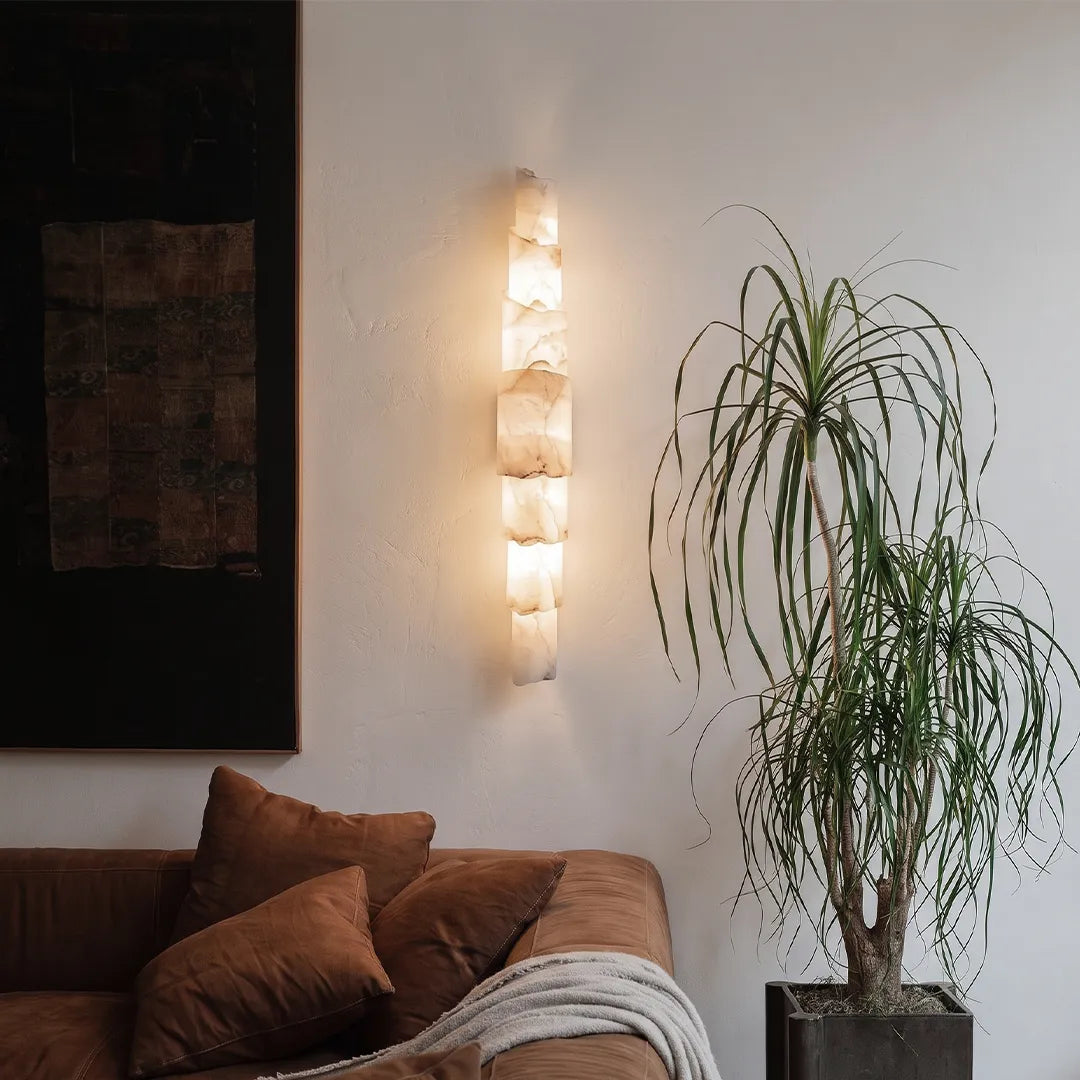 Sculptural wall sconce installed above a sofa with textured layered shades and warm decorative lighting.