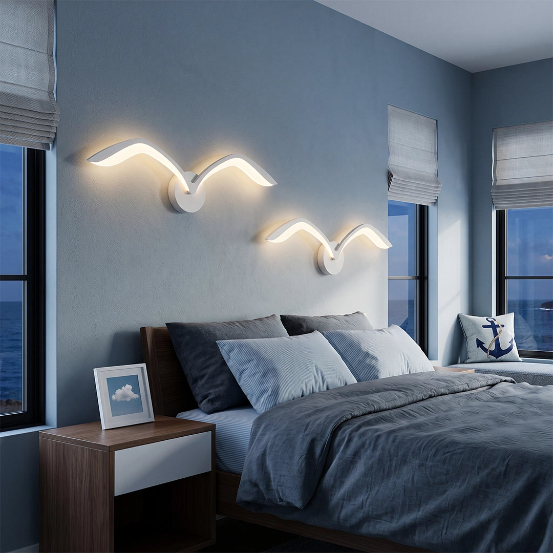 Seagull lighting sconces with wing-inspired curves mounted above a bed in a modern blue bedroom.