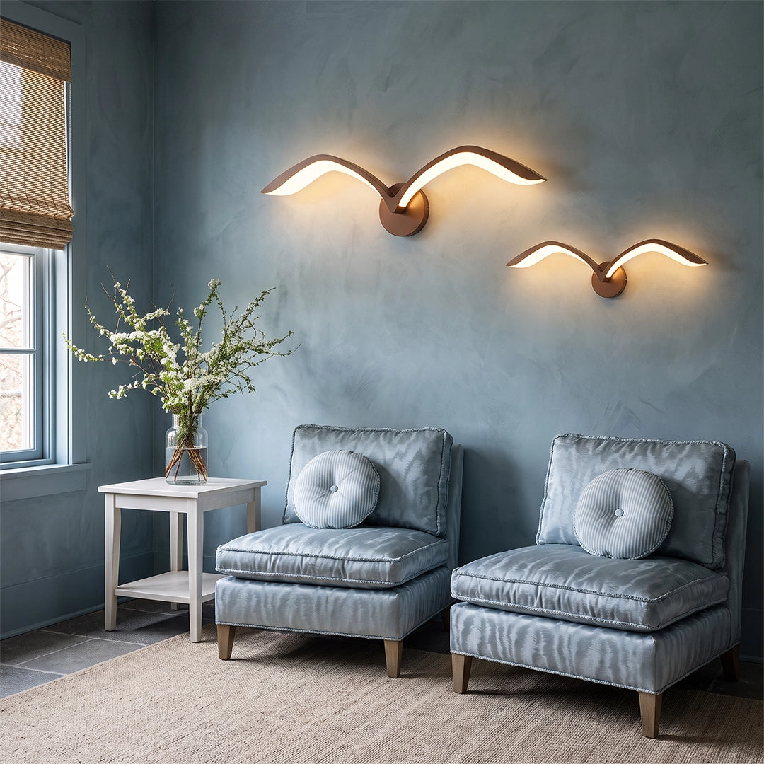 Seagull lighting sconces with sculptural bird-like shapes illuminating a cozy seating area with blue walls.