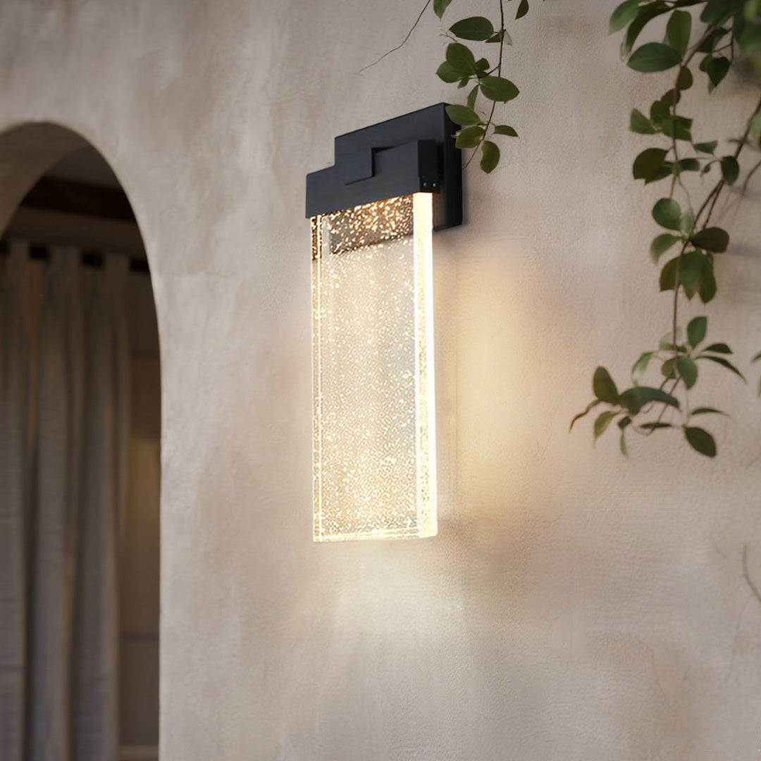 Seeded glass outdoor wall lighting mounted beside an arched doorway, providing warm illumination.