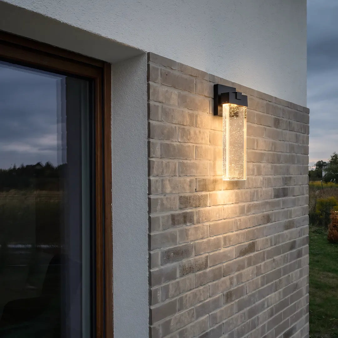 Seeded glass outdoor wall lighting fixed to a brick exterior wall beside a modern doorway.