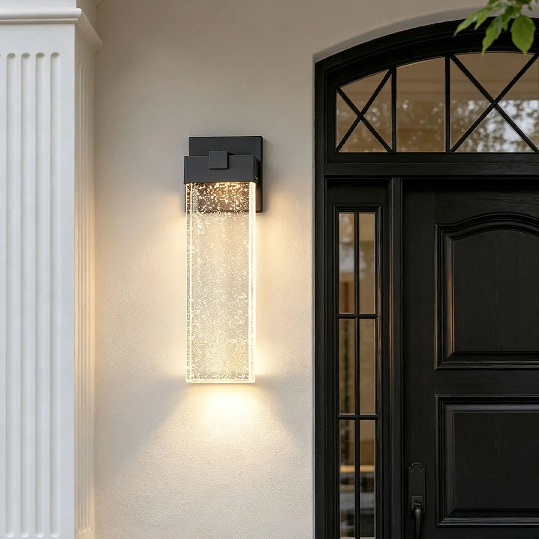 Seeded glass outdoor wall lighting beside an entrance featuring a black metal frame and decorative textured glass shade.