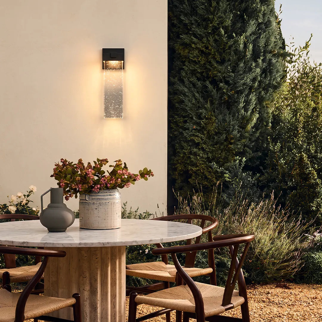 Seeded glass outdoor wall lighting illuminating an outdoor dining space with a warm ambient glow.