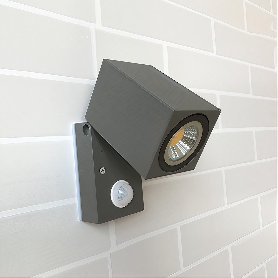 Sensor wall lights outdoor in black, angled design, mounted on a white brick wall.