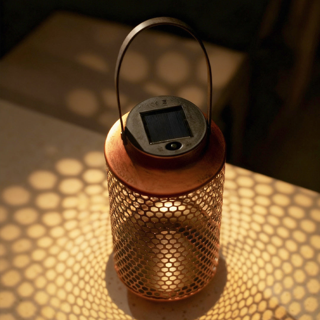 Portable solar lantern projecting decorative shadow patterns onto surrounding surfaces.