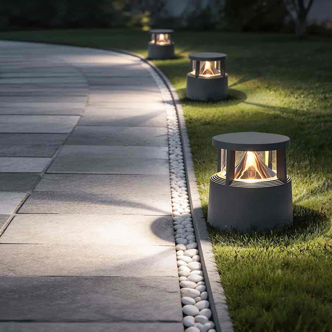 Short bollard light illuminating a modern garden pathway with warm ambient glow.