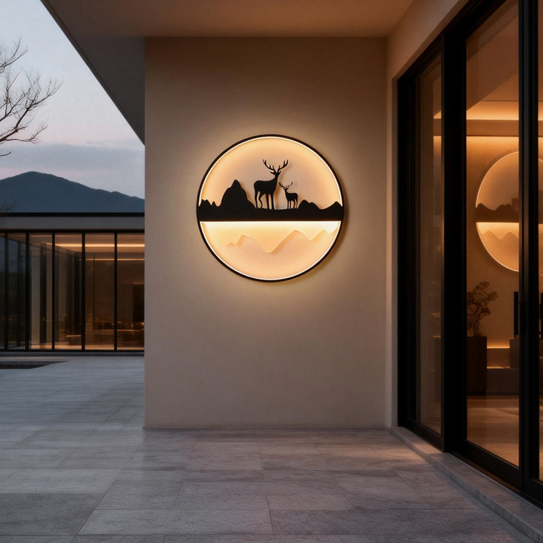 Silhouette wall light illuminating a modern patio entrance with deer and mountain design.