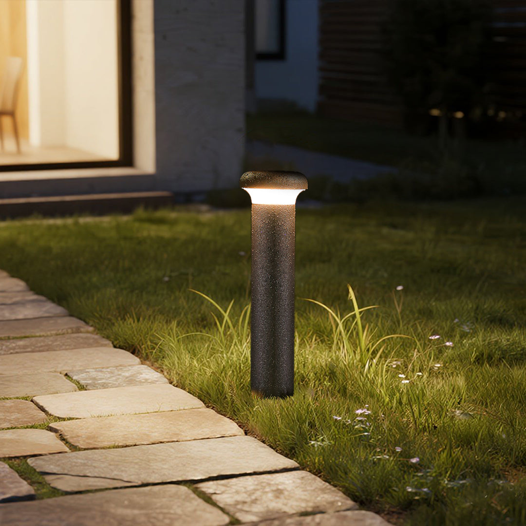 Single dark bollard light fixture standing on manicured grass area
