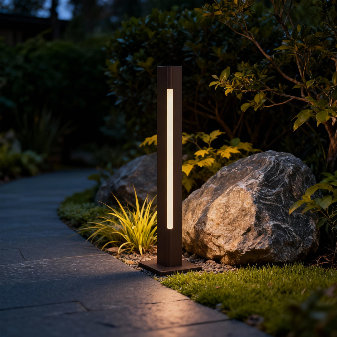 Bright silver led bollard light fixtures casting soft light along a contemporary home’s exterior pathway.