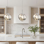 Elegant silver melt led pendant light trio over a modern marble kitchen island in bright room.