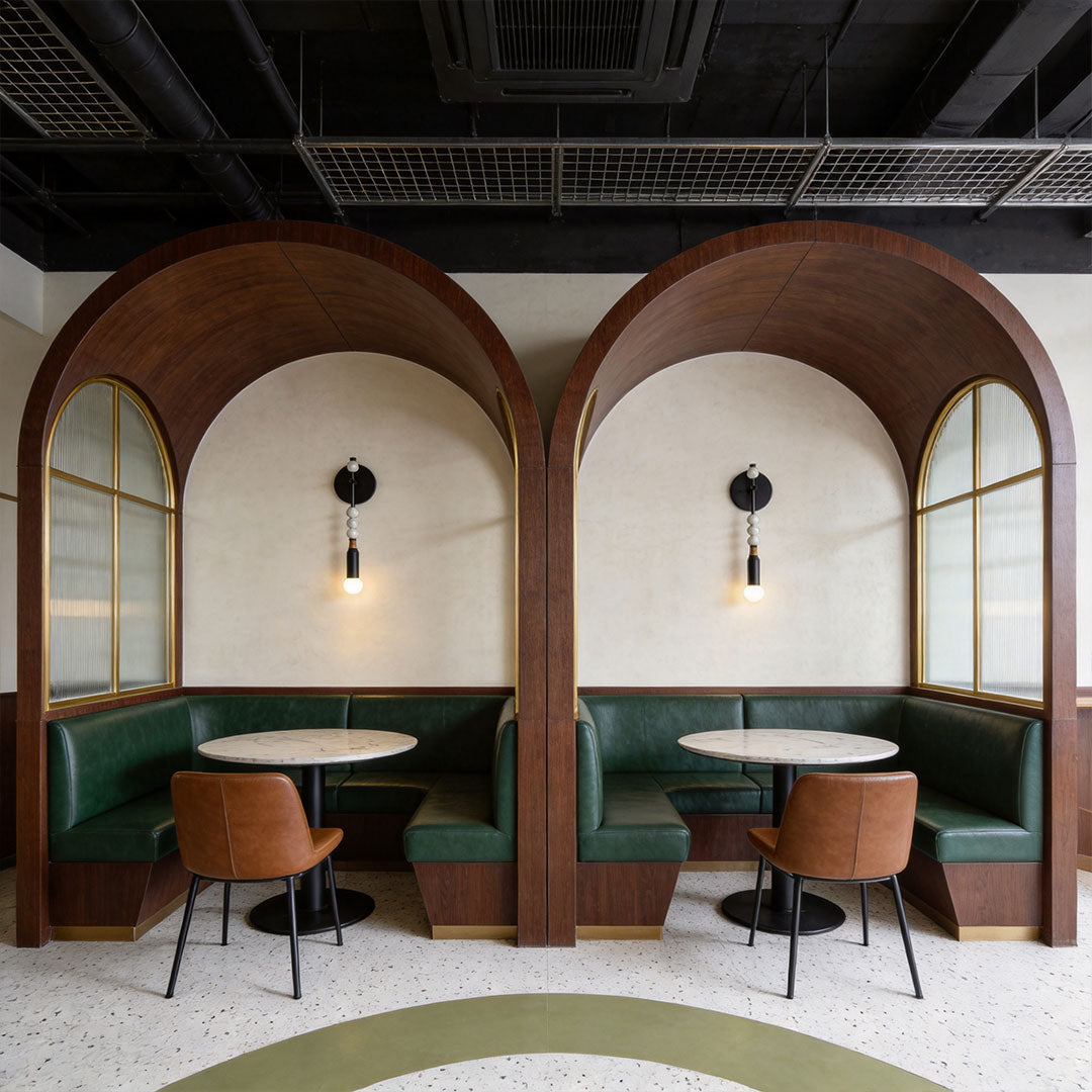 Elegant silver wall lights installed in arched restaurant booths creating warm decorative ambient lighting.