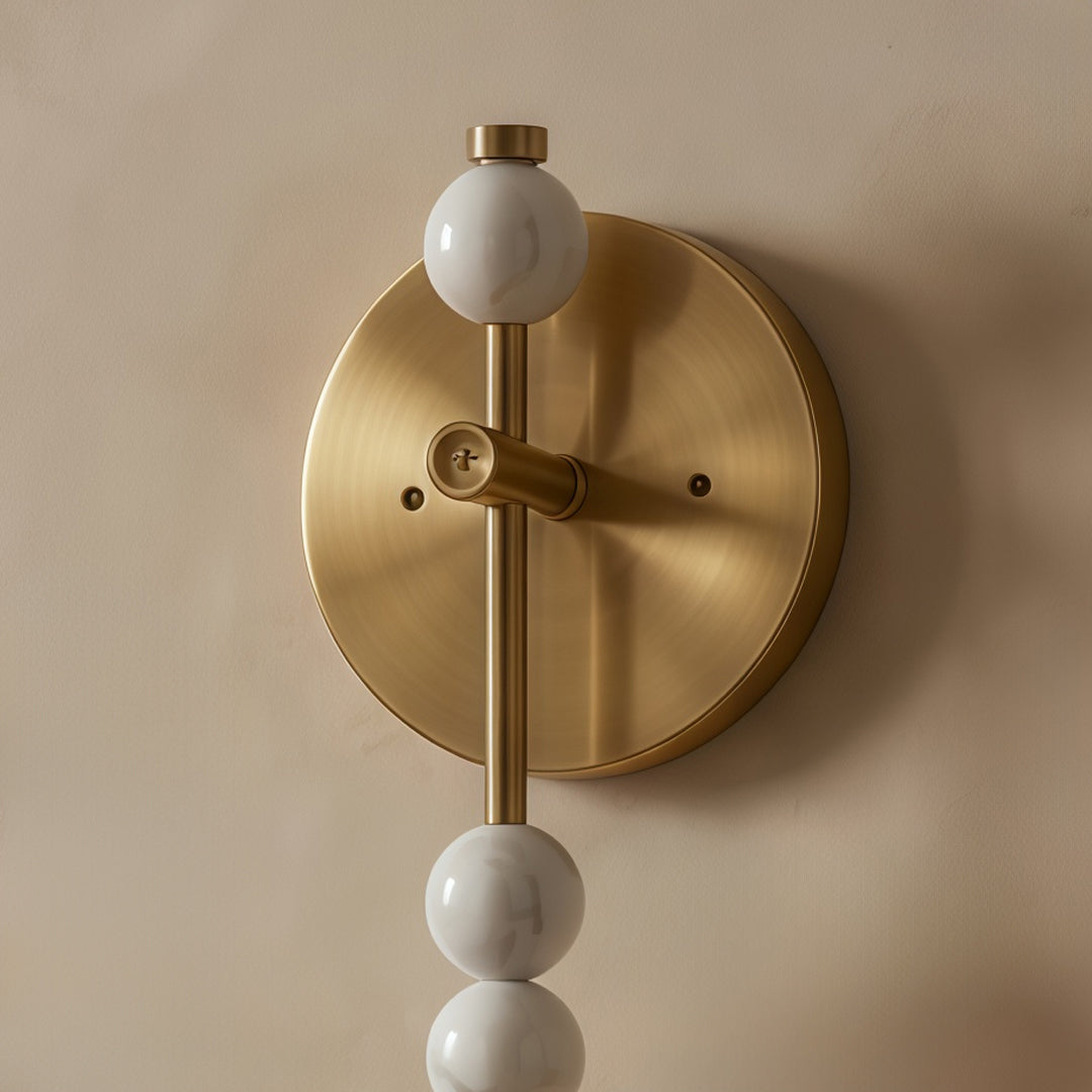 Detailed silver wall lights with circular brass backplate and dual globe decorative design mounted on wall.