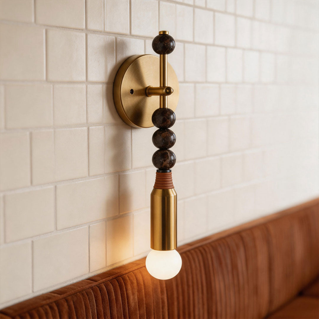 Contemporary silver wall lights with brass accents mounted on tiled wall in a stylish dining interior.