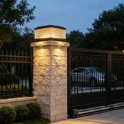 Large outdoor solar pillar lights mounted on stone gate columns creating elegant warm illumination at night.