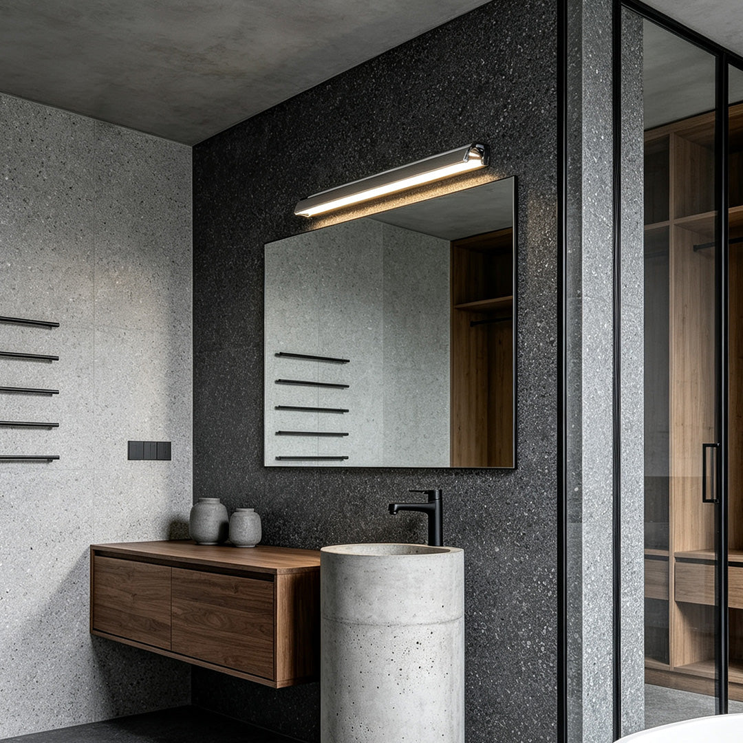 Elegant silver wall lights installed above a modern bathroom mirror with dark stone wall accents and warm lighting.