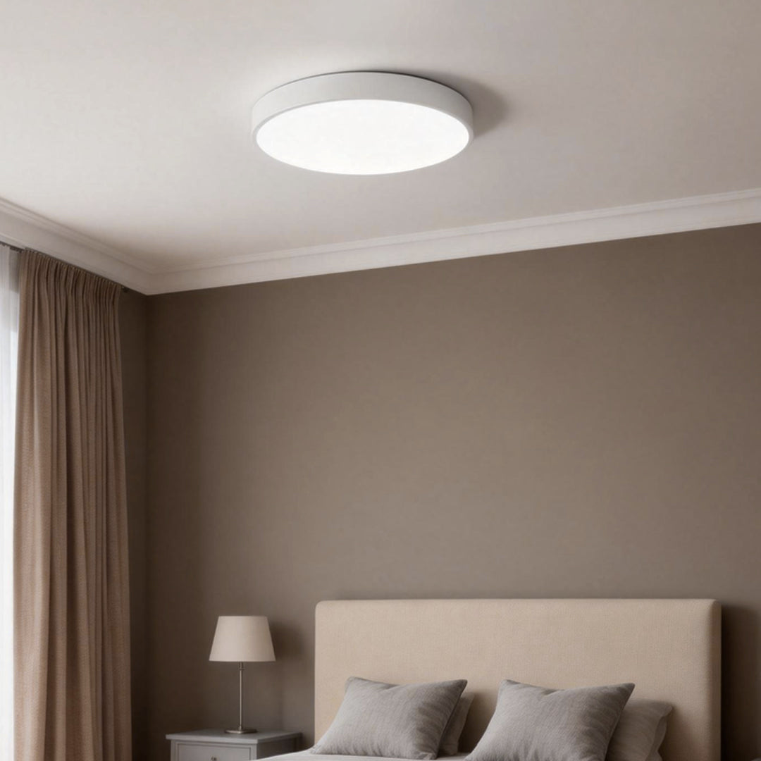 Simple flush mount ceiling light installed in a modern bedroom with neutral tones.