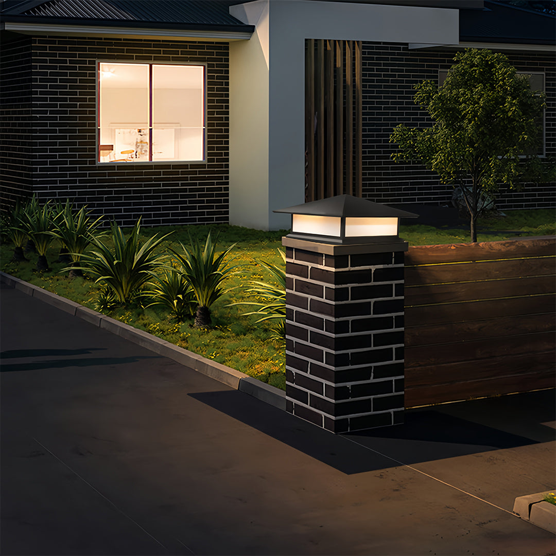 Single black pillar lights fixture on a brick gate post, illuminating the entrance pathway of a residential house.