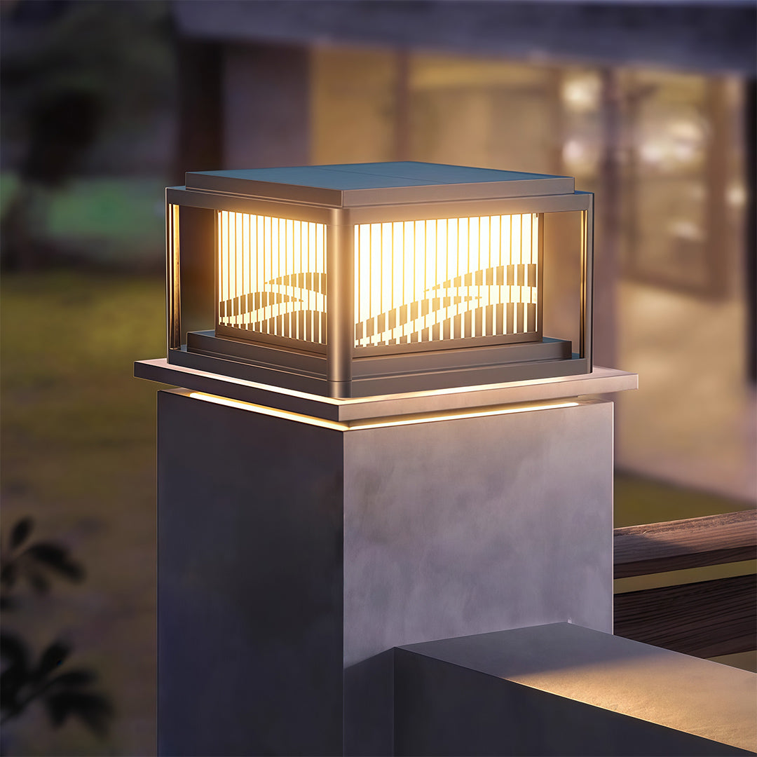 Single contemporary pillar light creating warm glow on grey concrete post with natural garden backdrop.