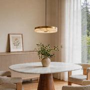 Single disc pendant light glowing above a round marble dining table in a serene modern room ok.