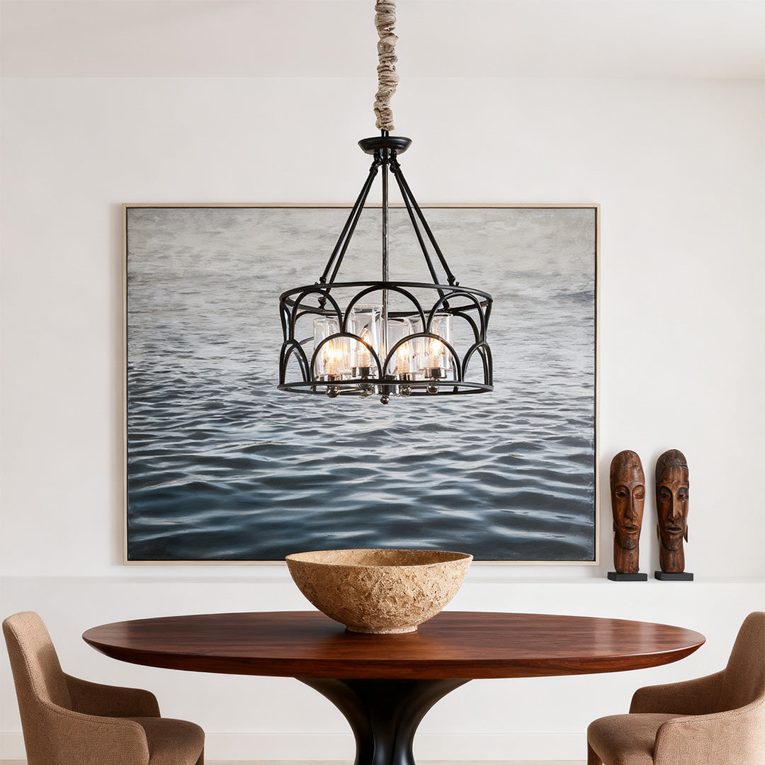 Single elegant chandelier with black wrought iron cage and clear glass shades, hanging over a rustic round wood dining table.