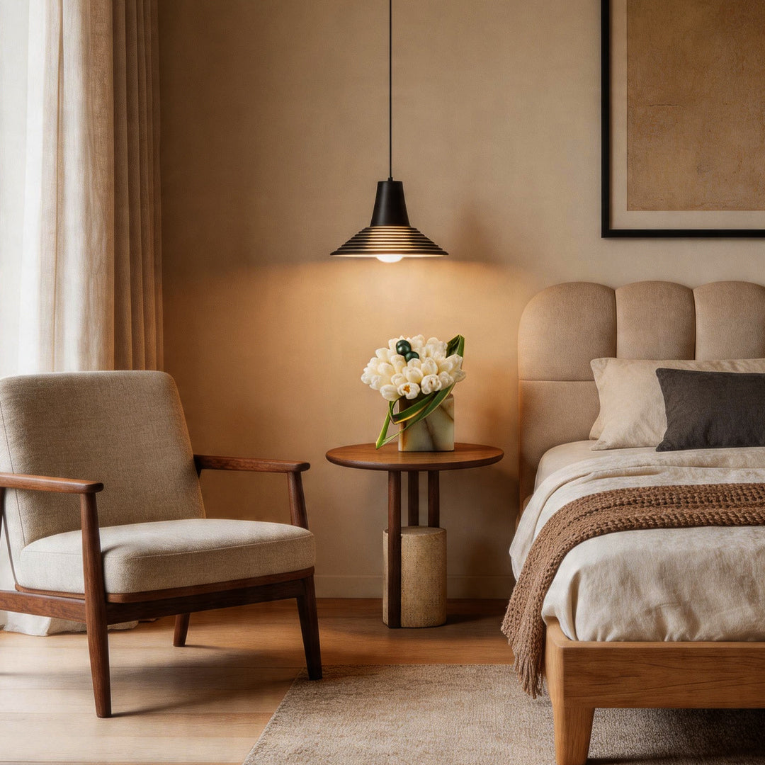 The single glass cone pendant light illuminating a bedside table in a cozy modern warm bedroom.