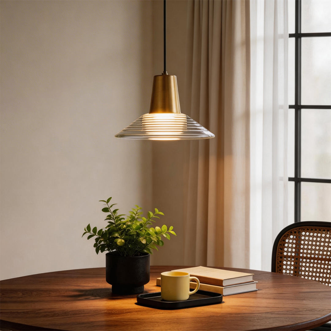 A single glass cone pendant light glowing warmly over a round wooden table by a bright window.