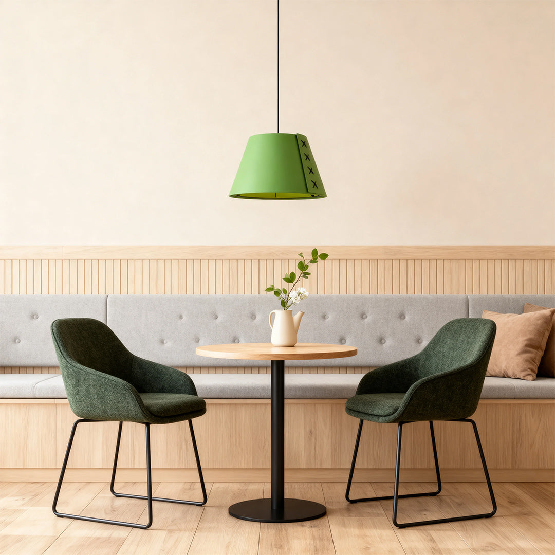 Close-up of a single green hanging pendant light illuminating a cozy restaurant booth area 