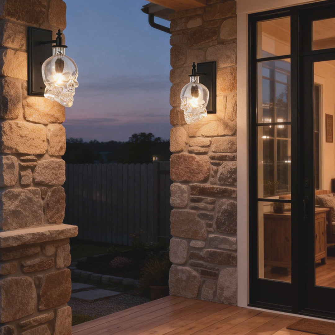Creative glass lamp shades for wall lights in skull shape, illuminating an outdoor patio during dusk with warm light.