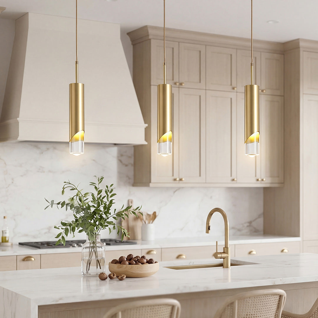 Trio of Slanted Gold Cylinder Pendant lights over a luxury marble kitchen island with cabinets.