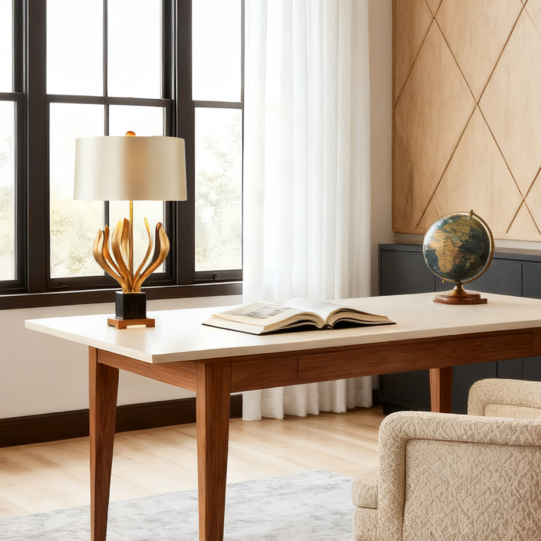 Elegant gold metal table lamp with sculptural base and beige lampshade in a contemporary study