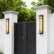 Two sleek black outside wall lights mounted on white pillars flanking a modern dark gate.