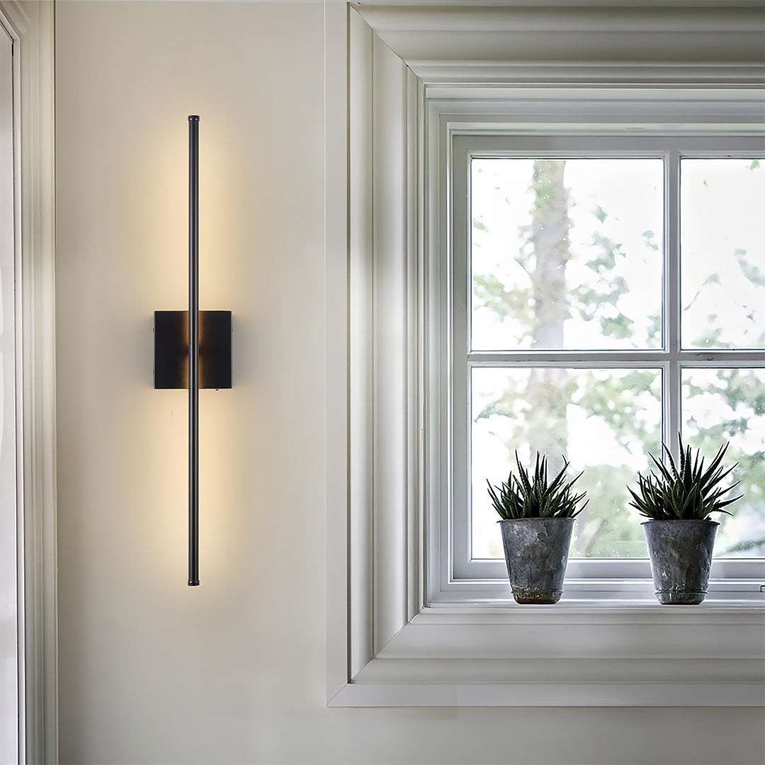 Sleek linear wall lights installed vertically beside a window, adding modern illumination to a bright room.