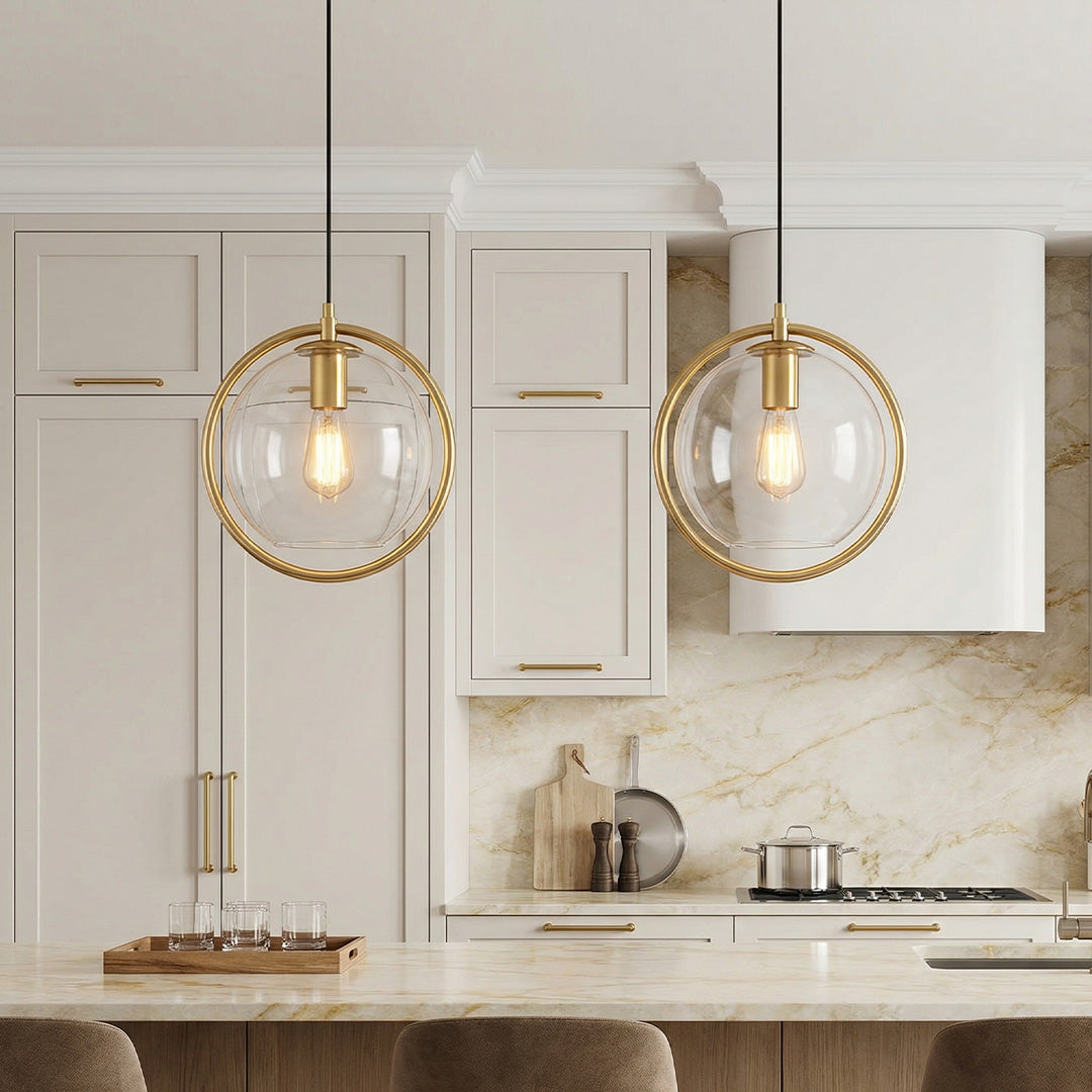 Sleek mini gold pendant light set with clear glass globes over a luxury marble kitchen island.