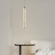 Sleek modern crystal pendant light with a cylindrical design, hanging elegantly in a minimalist living room.