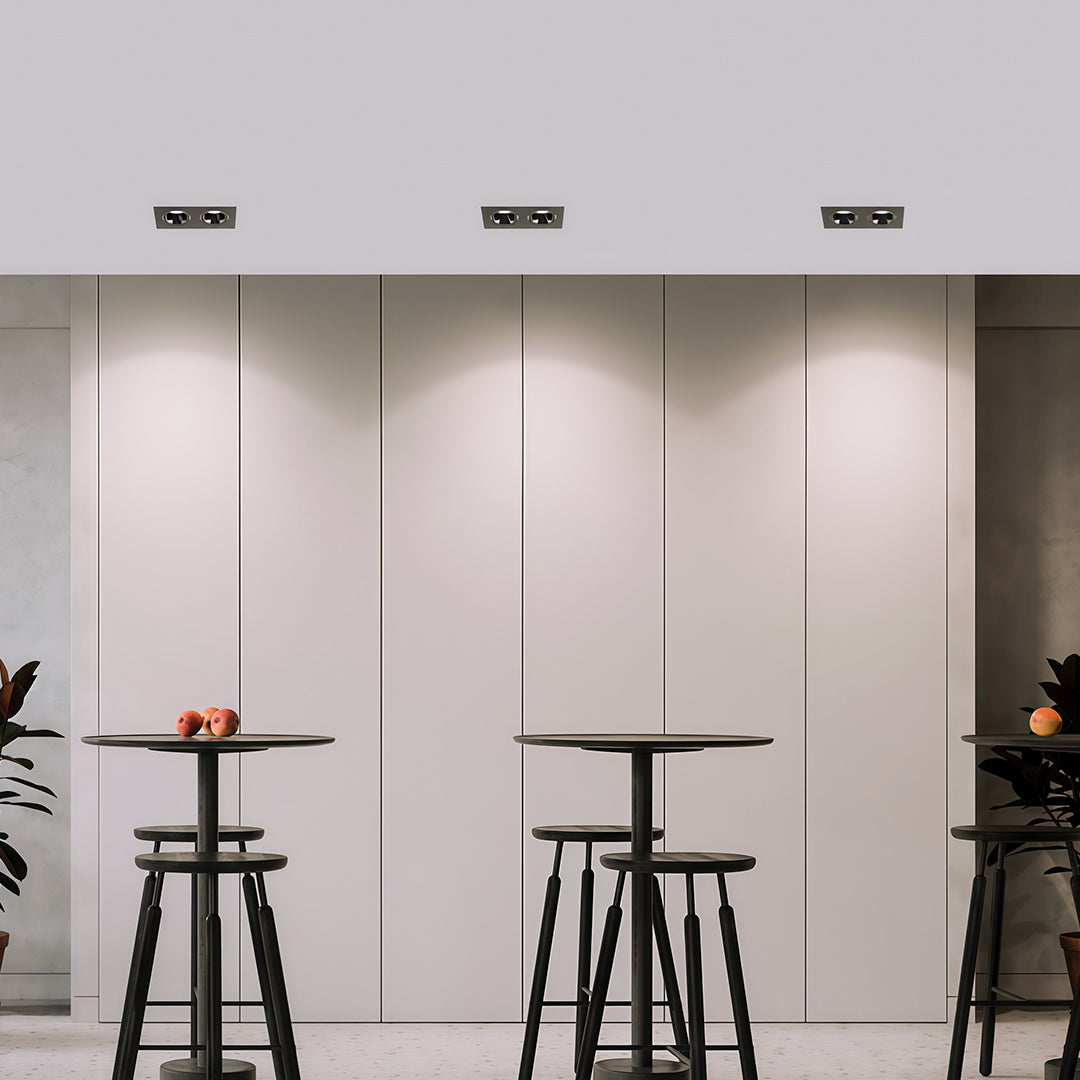 Sleek square recessed downlight fixtures installed above tall white cabinets in a minimalist modern room.