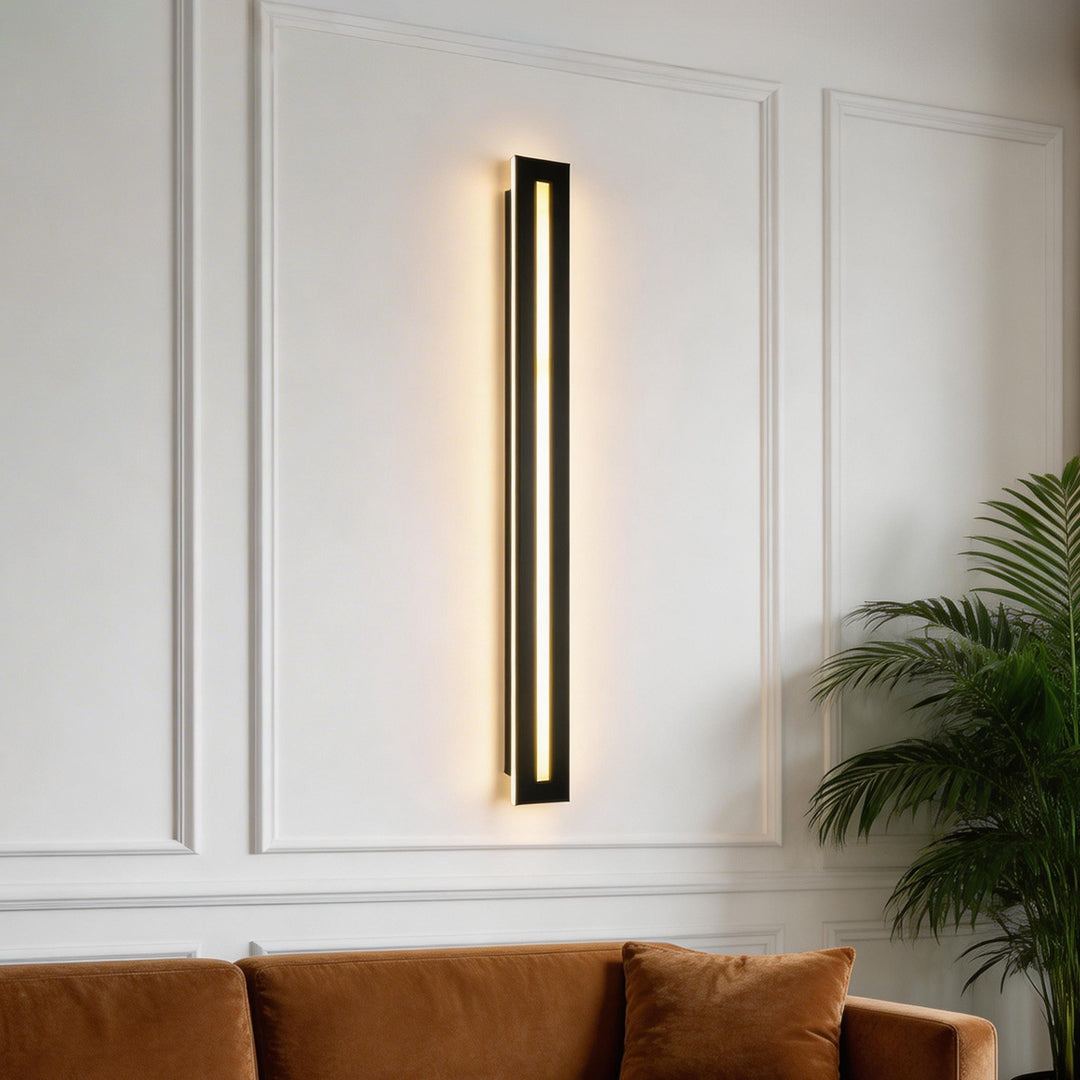 Sleek vertical long black wall sconces installed on a white paneled wall.
