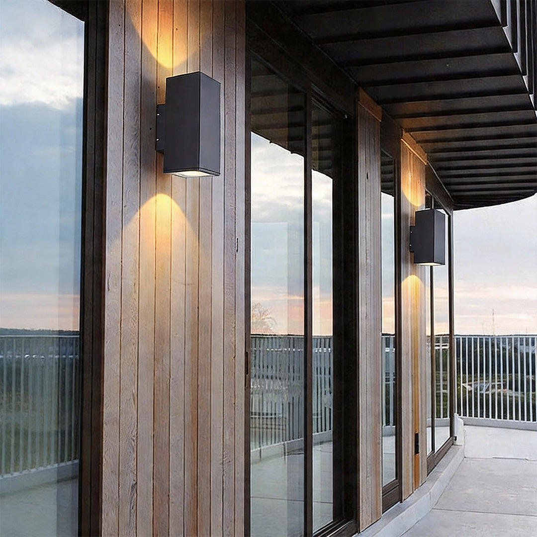 Sleek wall sconce up and down light glowing on a modern vertical wood slat exterior wall space.