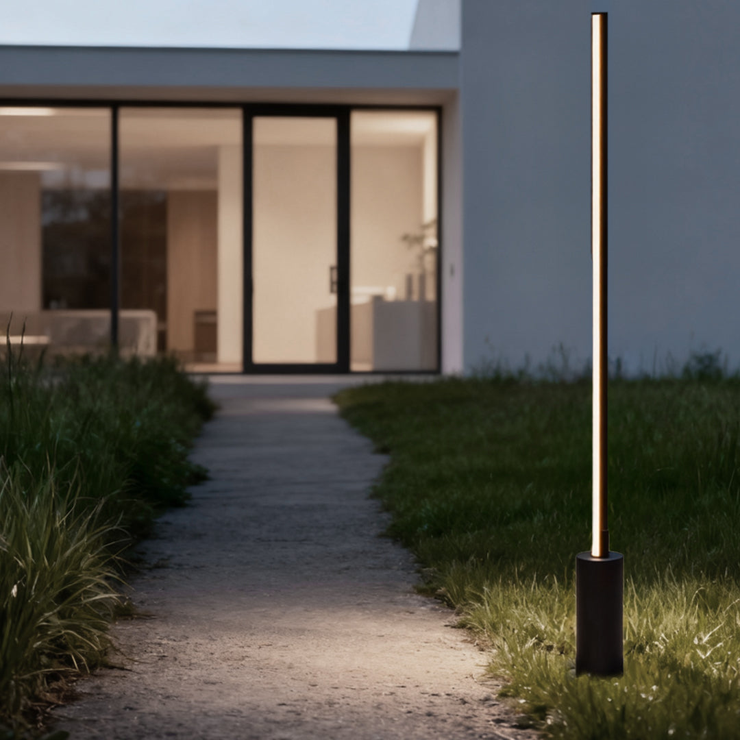 Slim contemporary outdoor floor lamps marking a residential pathway near a modern house entrance.