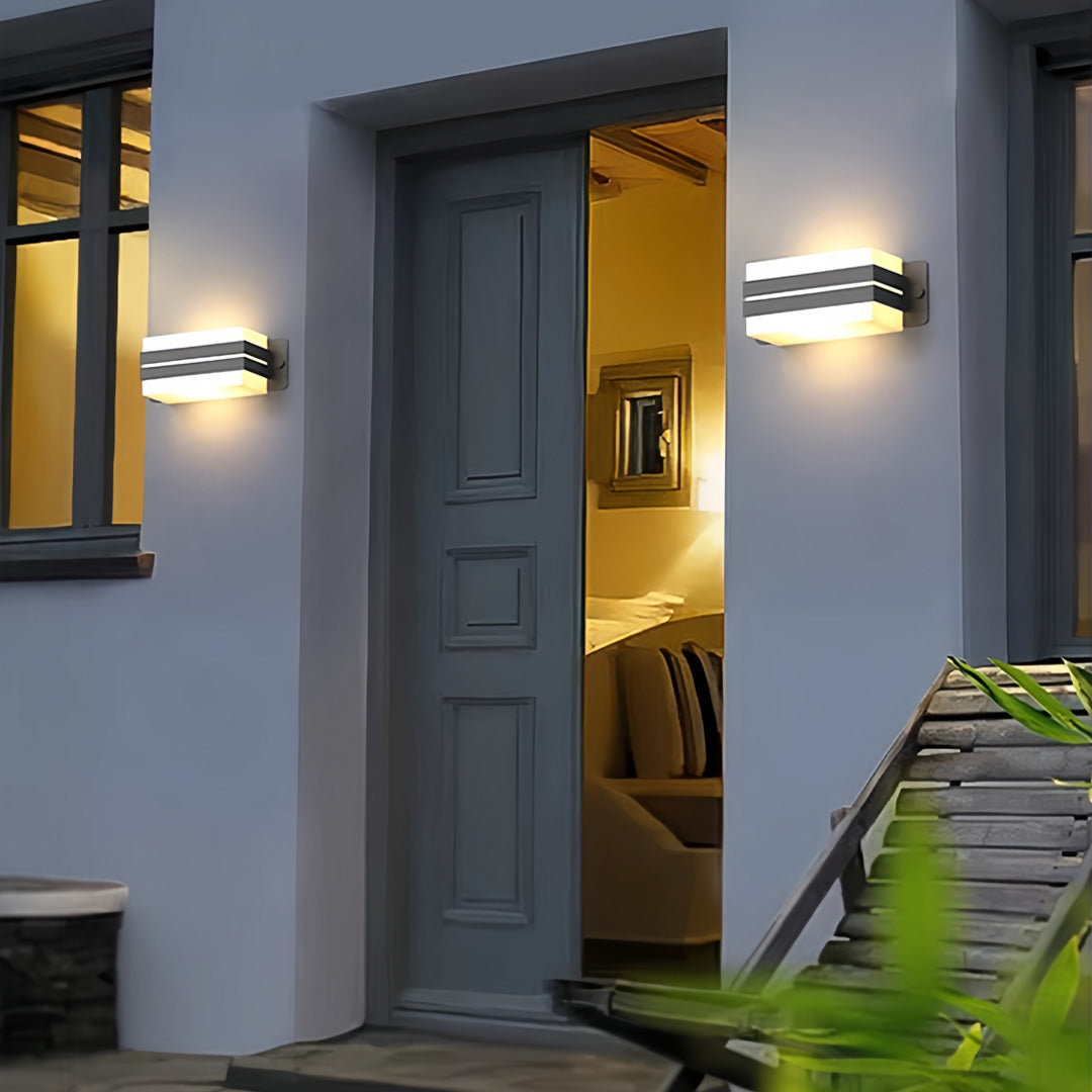 Tall entryway illuminated by slim linear outdoor wall sconce lighting in a modern architectural setting.