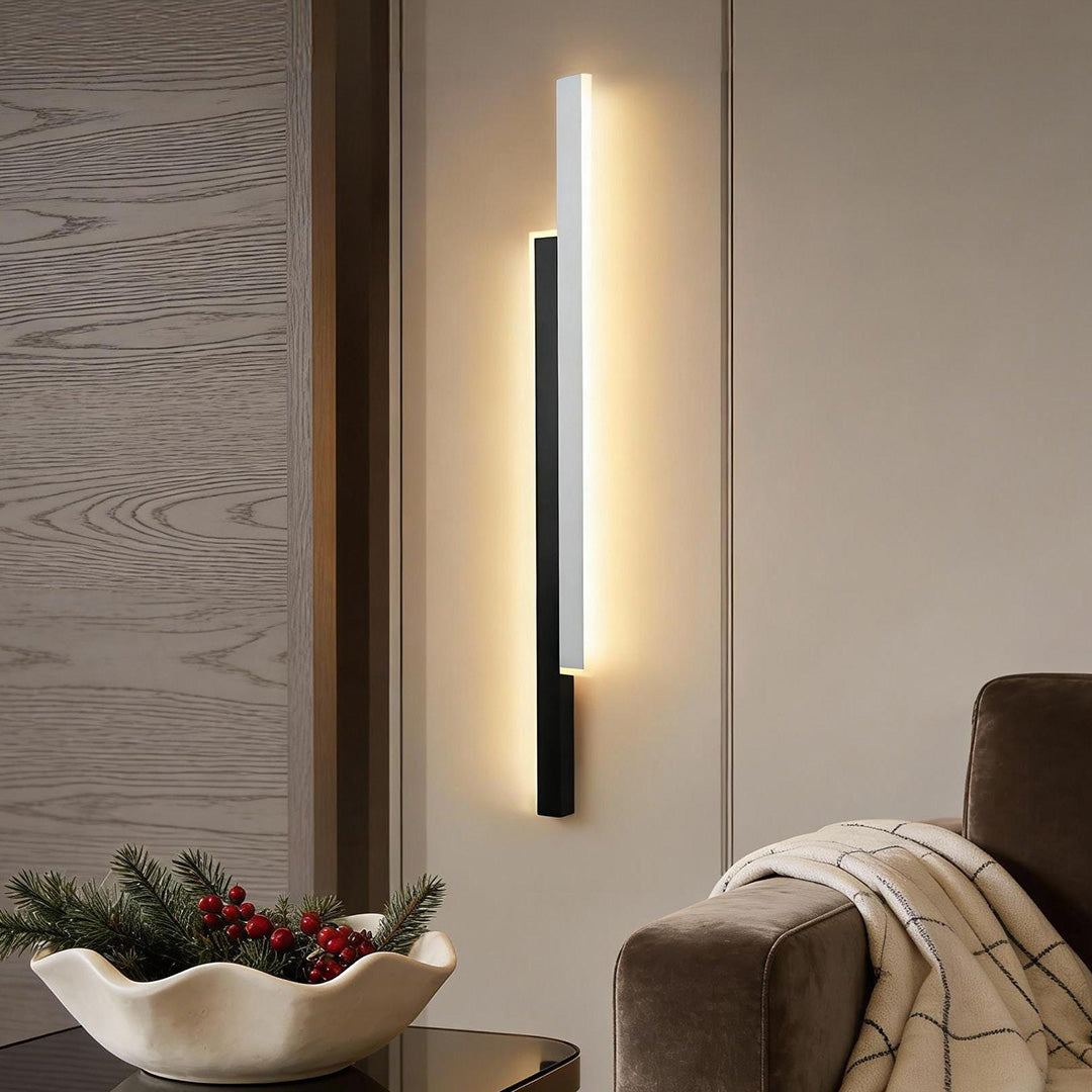 Slim vertical wall light on a textured wall above a console table in a refined lounge space.