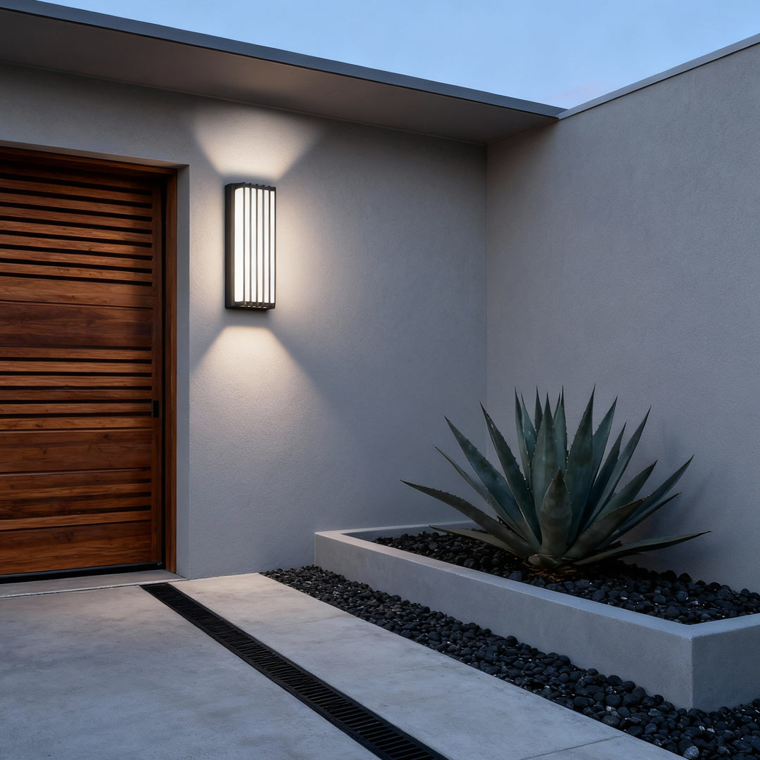 Slim wall-mounted linear lighting fixture installed outdoors, casting vertical ambient light against textured wall.