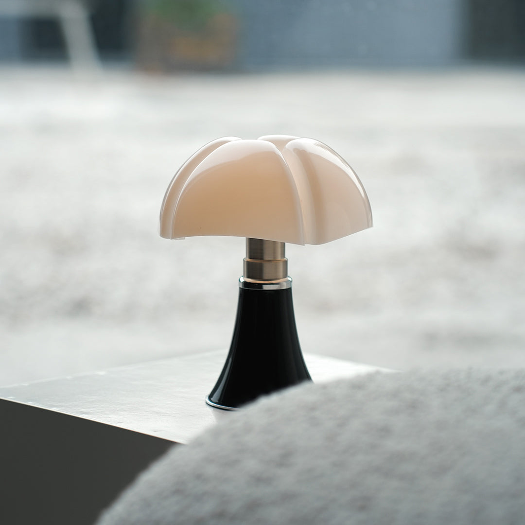 Small Bauhaus table lamp with white shade on gray surface near window.
