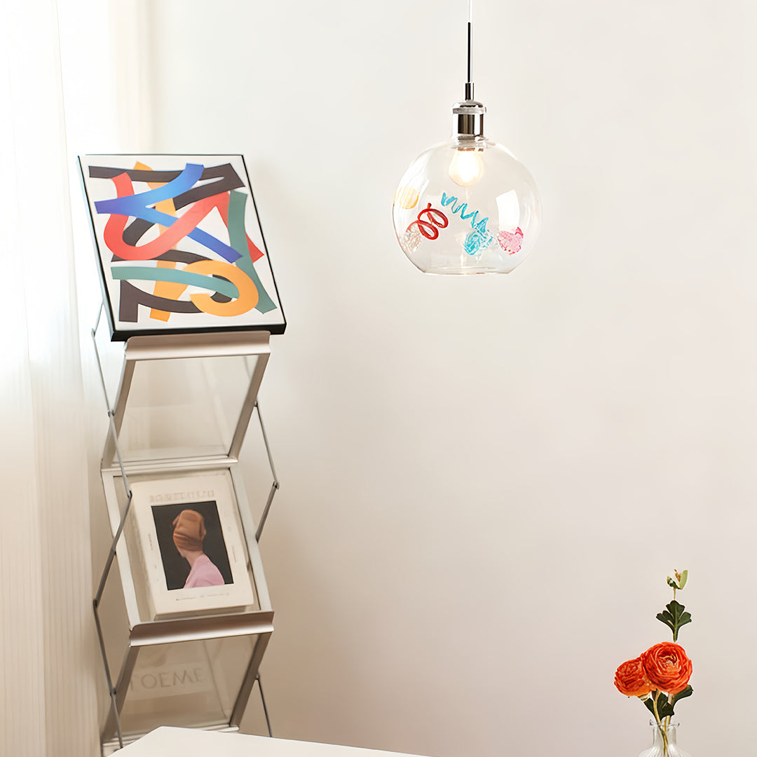 Small decorative coloured glass pendant lights suspended in a minimalist living space with white walls.