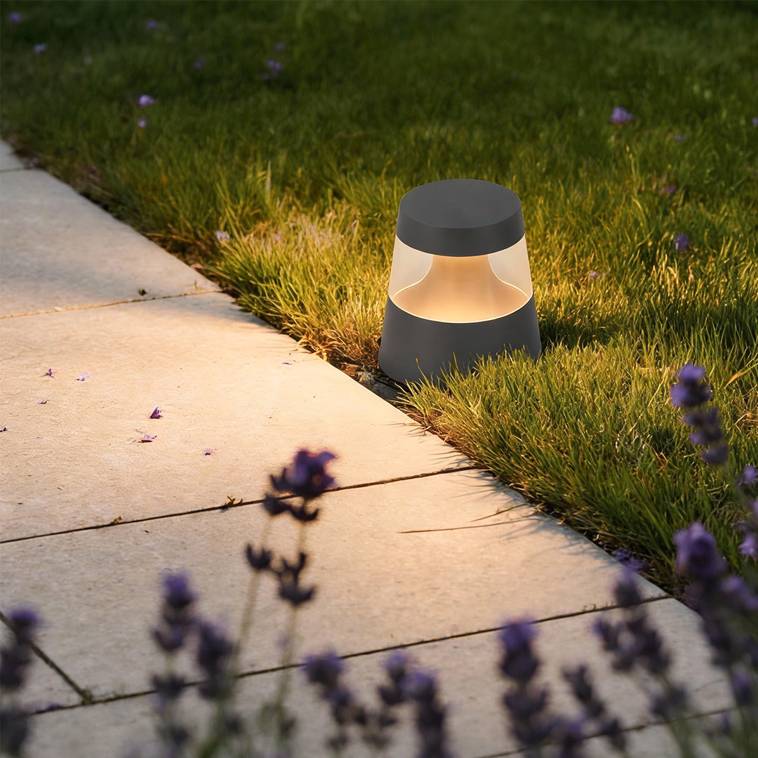 Compact small landscape lights lining a concrete walkway, casting a warm glow along the garden path and surrounding lawn.