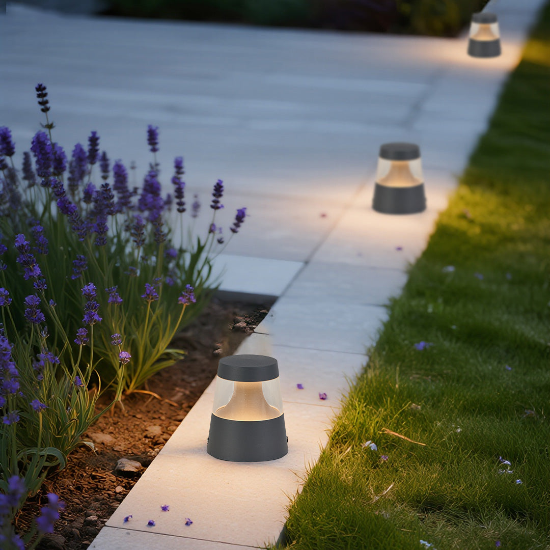 Low-profile small landscape lights installed near lavender plants, adding gentle illumination to a residential outdoor walkway.