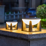 Two solar powered bollard lights in small and large sizes, shown glowing on a wet stone pillar at dusk.