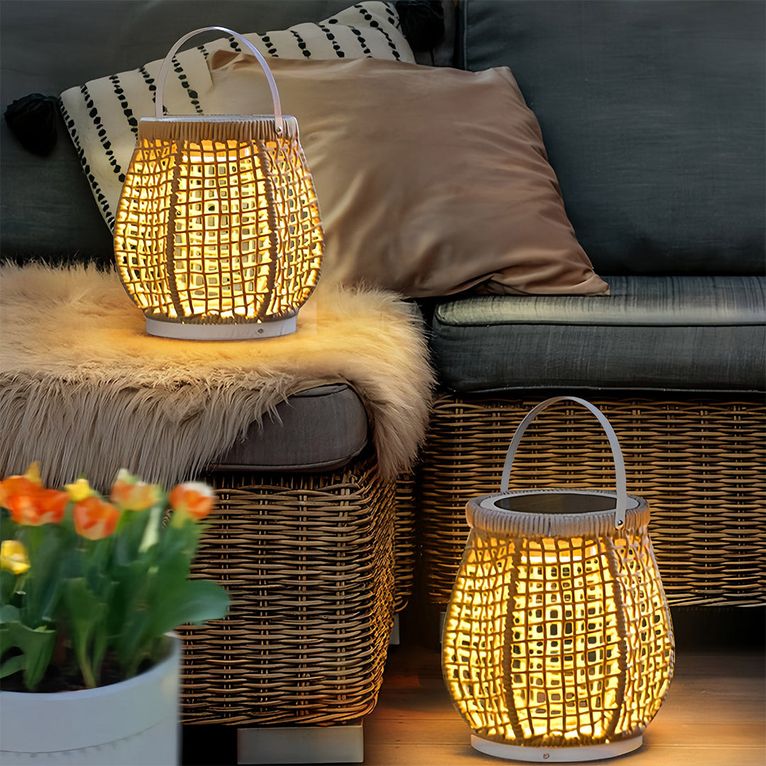 Small woven outdoor lanterns with a rope handle, providing a warm glow next to a textured rattan sofa on a cozy patio at dusk.